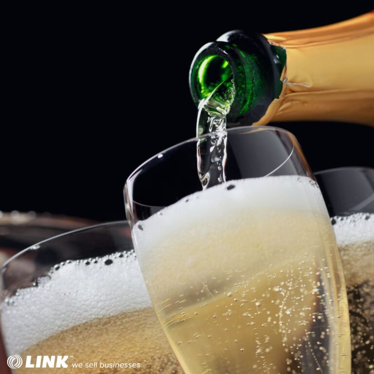 Champagne flowing from a bottle into a filled flute, with bubbles rising against a dark background