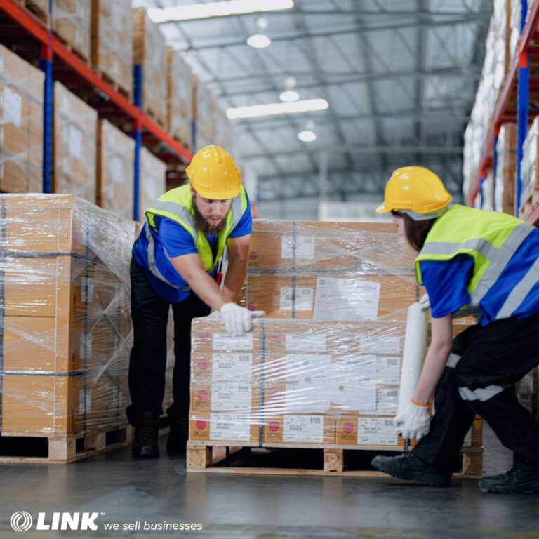 Warehouse workers wrapping pallets in distribution centre